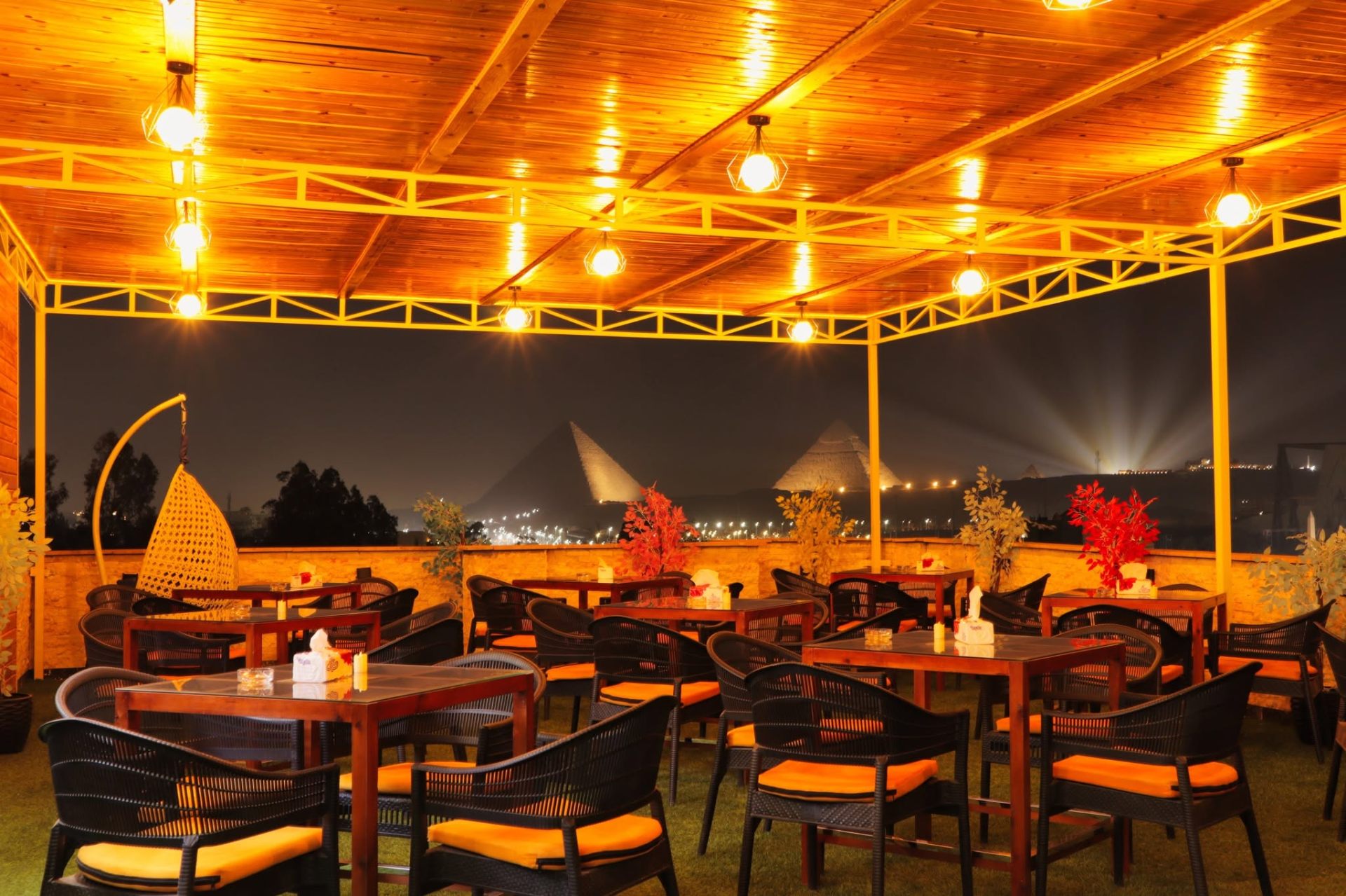 Grand View rooftop at night with the illuminated Pyramids of Giza on the horizon